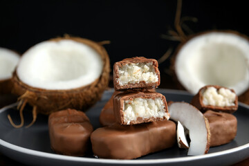 Delicious milk chocolate candy bars with coconut filling on grey plate, closeup