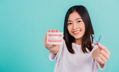Portrait young Asian beautiful woman smiling holding silicone orthodontic retainers for teeth retaining tools after removable braces, Female hold model teeth before, Orthodontics dental healthy care - obrazy, fototapety, plakaty