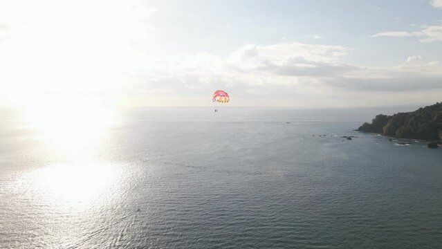 Parasailers kiting over the beautiful calm ocean off the coast of Manuel Antonio Beach on the Central Pacific Coast of Costa Rica. Aerial follow shot
