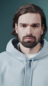 Isolated Dark-haired guy confused feels doubt while makes choice, dressed in casual hoodie