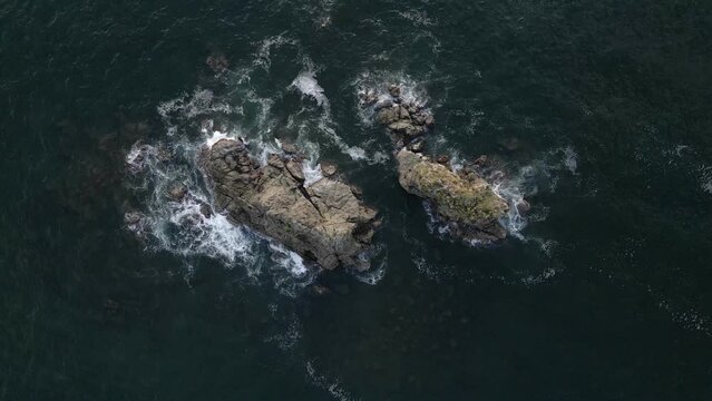 Wave slowly breaking over a rocky reef in the deep blue ocean in Costa Rica. Aerial top down view
