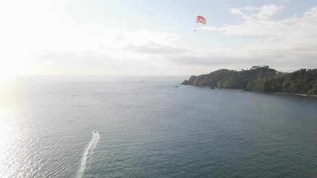 Parasailer glides over the ocean along the tropical coastline of Manuel Antonio Beach on the Central Pacific Coast of Costa Rica. Wide angle aerial