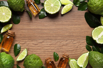Frame of glass bottles with bergamot essential oil and fresh fruits on wooden table, flat lay. Space for text
