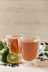 Glass cups of tasty bergamot tea and fresh fruits on white wooden table