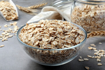 Glass bowl with oatmeal on grey table, closeup