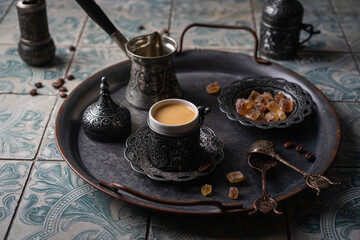 Coffee in metal Turkish traditional cup and coffee beans on tile background