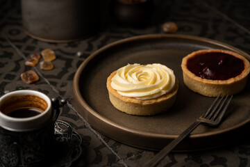 Mini tart with whipped cream and lemon sweet dessert on dark tile background