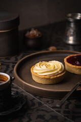 Mini tart with whipped cream and lemon sweet dessert on dark tile background