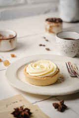 Mini tart with whipped cream and lemon, sweet dessert on white plate