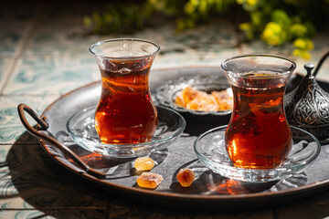 Turkish tea in traditional glass on tray closeup, tile background