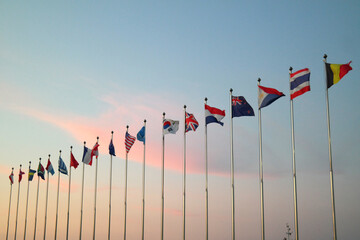 The flags of various countries are raised against the backdrop of sunset.