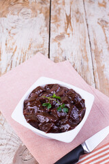 Raw liver on a white plate on a wooden background. Beef liver, top view. Offal in its raw form.