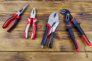 Set of different pliers on wooden background. Top view