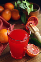 Tasty sicilian orange juice in glass and fruits on wooden table