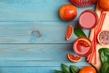 Tasty sicilian orange juice and fruits on light blue wooden table, flat lay. Space for text