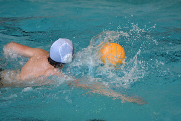 Young men play water polo in an indoor pool 