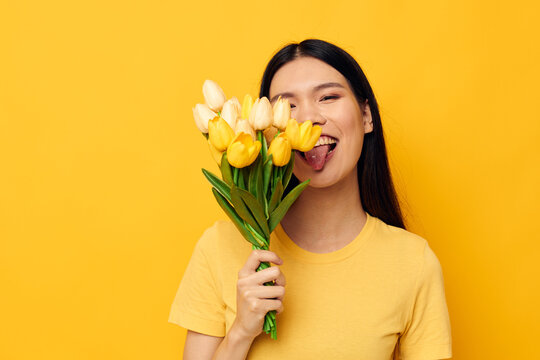 Charming young Asian woman bouquet of flowers in hands spring fun posing yellow background unaltered