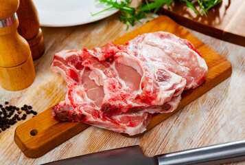 Chuletas de lomo, fresh loin pork chops on a wooden kitchen board with knife
