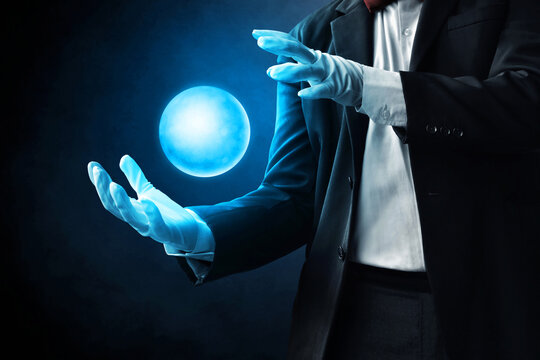 Magician hand showing magic trick on dark background