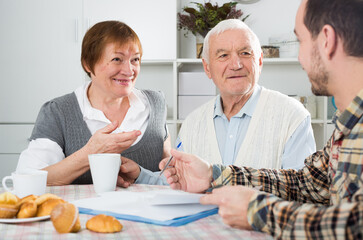 Elderly man and woman with employee of social department filled data form