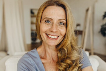 Senior woman-blogger with long golden hair, pretty freckled face, blue eyes and charming smile...