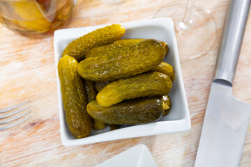 Closeup of pickled cucumbers on a white ceramic plate on a table in a restaurant
