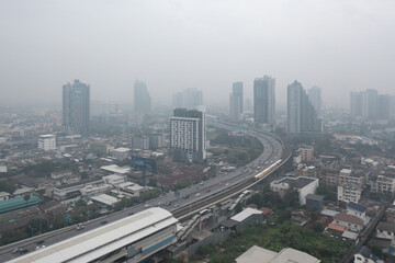 Naklejka na ściany i meble Aerial view of highway street road at Bangkok Downtown Skyline, Thailand. Financial district and business centers in urban city in Asia. Skyscraper buildings with fog. Air pollution pm2.5