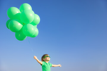Happy child with green balloons outdoor