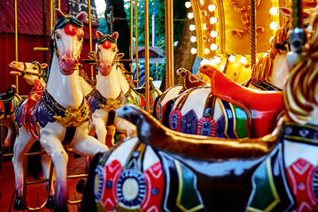 Fototapeta na wymiar Carousel with colorful horses at amusement park, Merry go round with horse, Vintage ride attraction for children