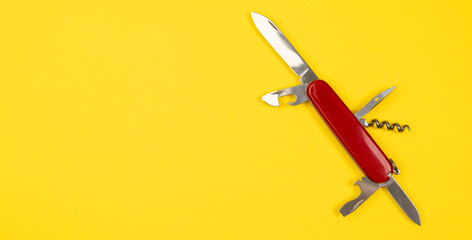 Jack of all trades concept with Swiss Army multi tolls pocket knife isolated on yellow background. Red military knife with copy space.