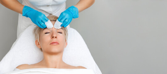 Naklejka premium Professional cosmetologist does a deep mechanical cleaning forehead of the client's face. Top view. Acne treatment concept