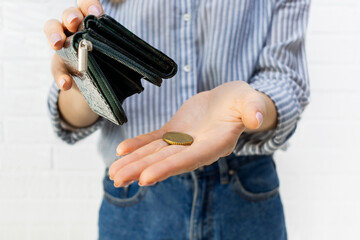 Close-up of a young womans hands pours the last coin out of an open wallet. No money, bankruptcy, financial problems, crisis, unemployment, lack of funds to pay expenses concept.