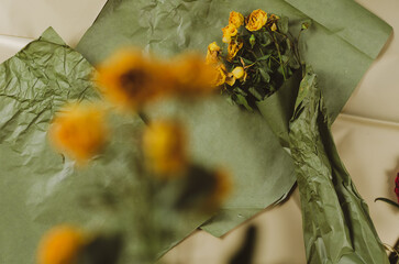 Yellow roses against a beige-green background. Fading bouquet of flowers. View from above....