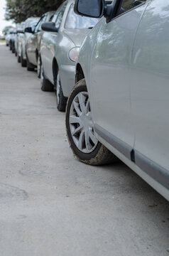 Rows of cars parked on the side of the road in a residential area. Lots of gray cars parallel to the sidewalk. Parallel parking.