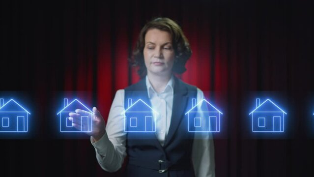 A business woman scrolls through holograms of houses. A realtor is trying to find real estate. When she reaches the green neon house, she clicks on the picture and it increases. The choice is made.