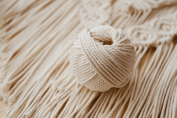 White natural cotton macrame cord in a roll on a handmade wall hanging.