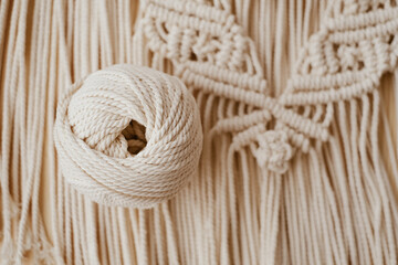 Fototapeta na wymiar White natural cotton macrame cord in a roll on a handmade wall hanging.