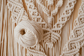 White natural cotton macrame cord in a roll on a handmade wall hanging.