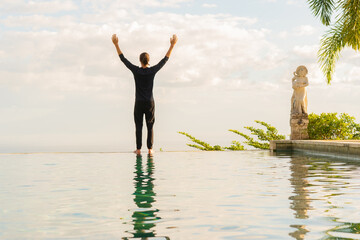 Fototapeta premium A man standing at the edge of infinity pool