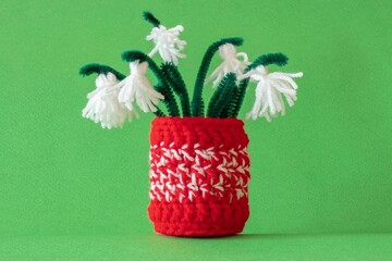 Close up red and white yarn strains of crochet vase and tassel snowdrops flowers as martenitsa,...