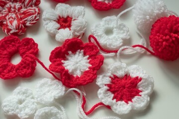 Close up crochet flowers of red and white yarn strains as martenitsa - bulgarian folklore tradition in March. Baba Marta day. Shallow depth of focus. Light background.