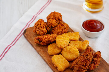 Tasty Fastfood: Chicken Nuggets, Wings and Tenders with Ketchup and Beer, side view. Space for text.