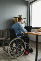 Handicapped Businessman Sitting On Wheelchair And Using Computer In Office