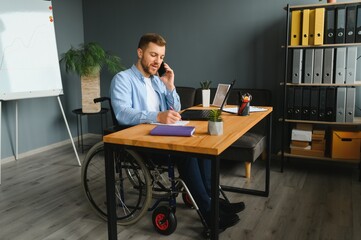 Young happy entrepreneur in wheelchair working on laptop at home.