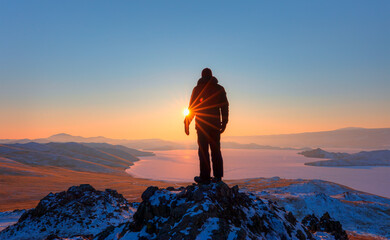 A man watching the view from the top of the hill - Beautiful winter landscape of frozen Baikal Lake. Panoramic view of the natural landmark of Olkhon Island at sunset - Baikal lake, Siberia  