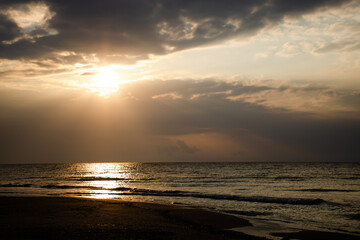 Beautiful sunrise on the sea, the sun's rays pass through the clouds. Calm weather, vacation concept