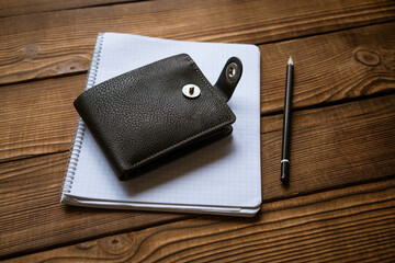 Business and finance concept. View of pen wallet and notebook on wooden table. Cost planning.