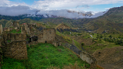 Fototapeta na wymiar View of the town of Chokh with abandoned houses against the backdrop of a valley with mountains and clouds