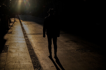 Silhouette of adult man in hat on street during sunset. Madrid, Spain - obrazy, fototapety, plakaty