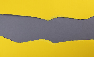 Yellow paper with torn edges isolated with grey colored paper background inside. Good paper texture